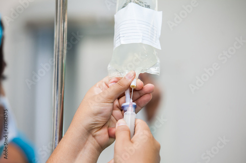 Nurse injecting a drug through an infusion system photo