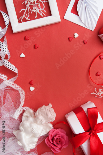 Flat lay on Valentine's Day with copy space for text. Gift, envelope, heart and hearts, angel, frame and rose on red background photo