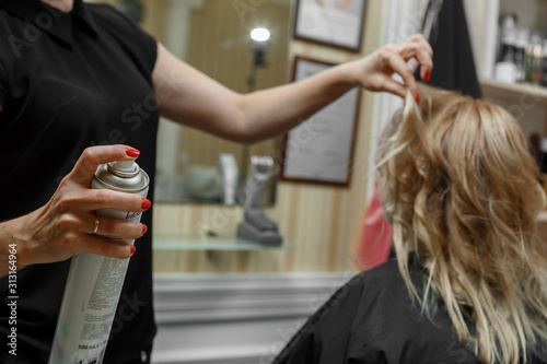 process of hair styling in hairdressing salon. studying hairdressing. Professional hairdresser working with client . hair styling using a hair lacquer. hairdresser with hairspray in hands close up.