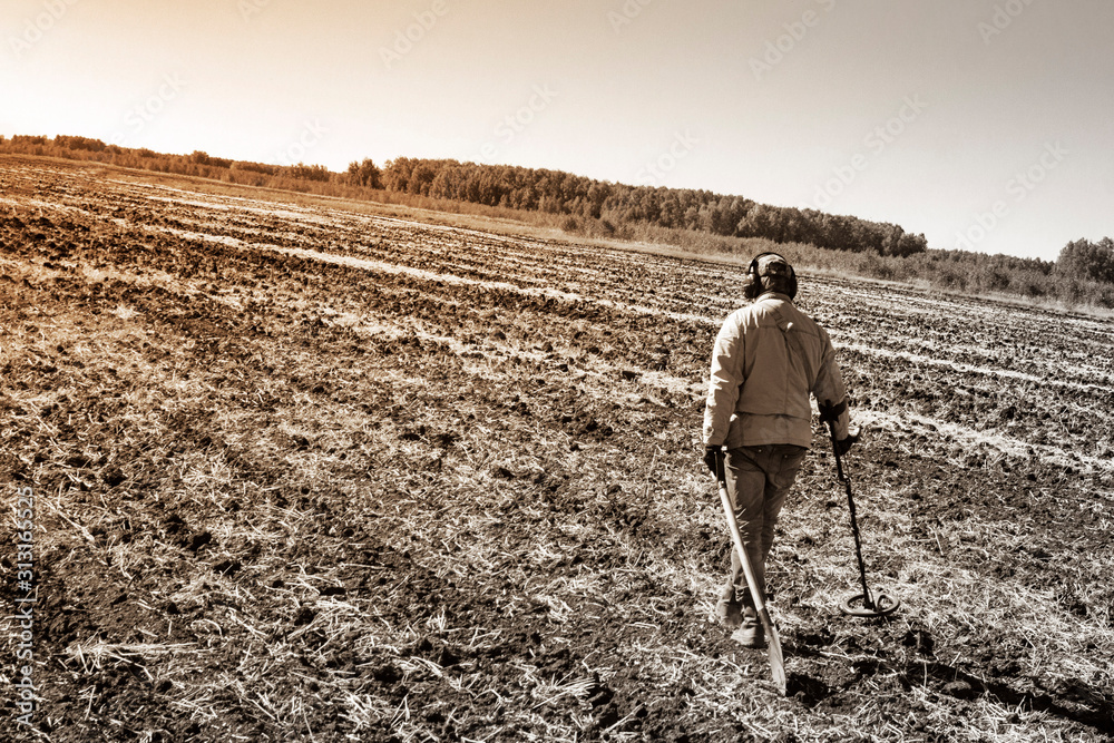 man on a treasure hunt with a metal detector in the woods on the field man on a treasure hunt with a metal detector in the woods on the field