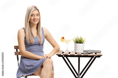 Young woman sitting at a table with a cocktail and looking at the camera photo