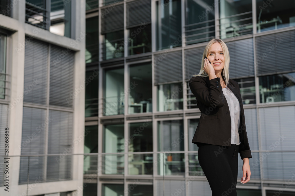 Blond businesswoman using smartphone in the background modern building Blond businesswoman using smartphone in the background modern building