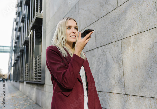 Blond businesswoman using smartphone in the city photo