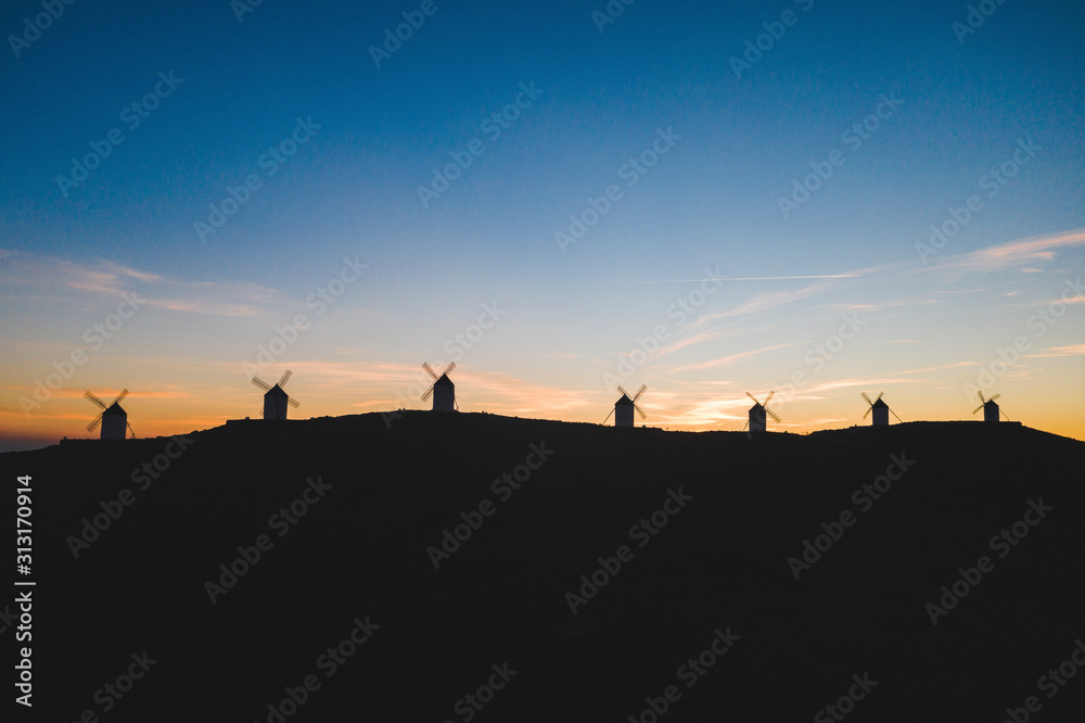 Silhouettes of windmills standing on top of hill at dawn Silhouettes of windmills standing on top of hill at dawn