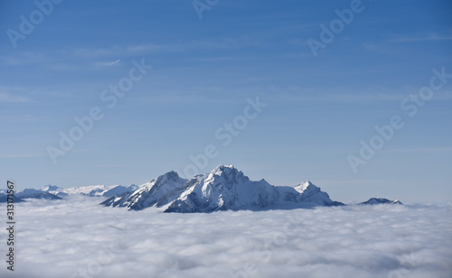 The top of a swiss mountain in the alps surrounded by clouds in winter
