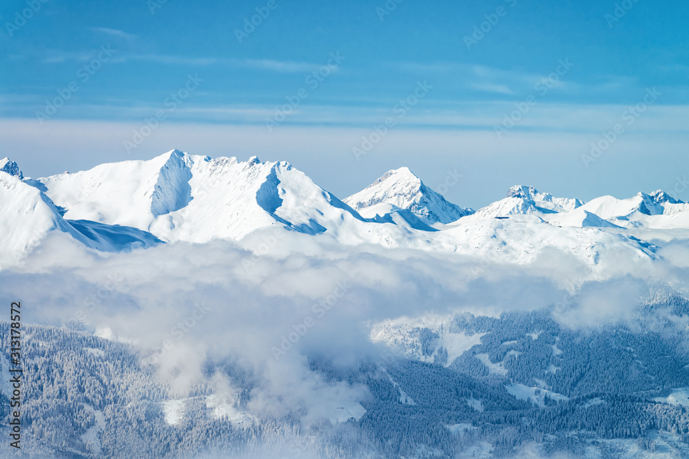 Landscape of Zillertal Arena ski resort in clouds in Tyrol in Mayrhofen in Austria in winter Alps. Alpine mountains with white snow and blue sky. Downhill peaks at Austrian snowy slopes.