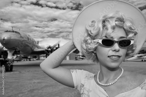 A woman wearing a classic outfit in front of a restored Lockheed L-1049 Super Constellation propeller aircraft