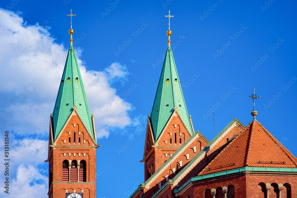 Green towers of Franciscan Church in Old city in Maribor in Slovenia in Europe. Cityscape with Medieval Basilica in Lower Styria in Slovenija. Travel and tourism. Blue sky background.