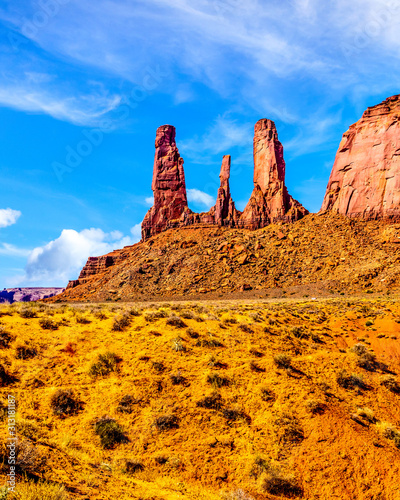 The towering red sandstone formations of the Three Sisters pinnacles and Mitchell Mesa in Monument Valley Navajo Tribal Park desert landscape on the border of Arizona and Utah, United States photo