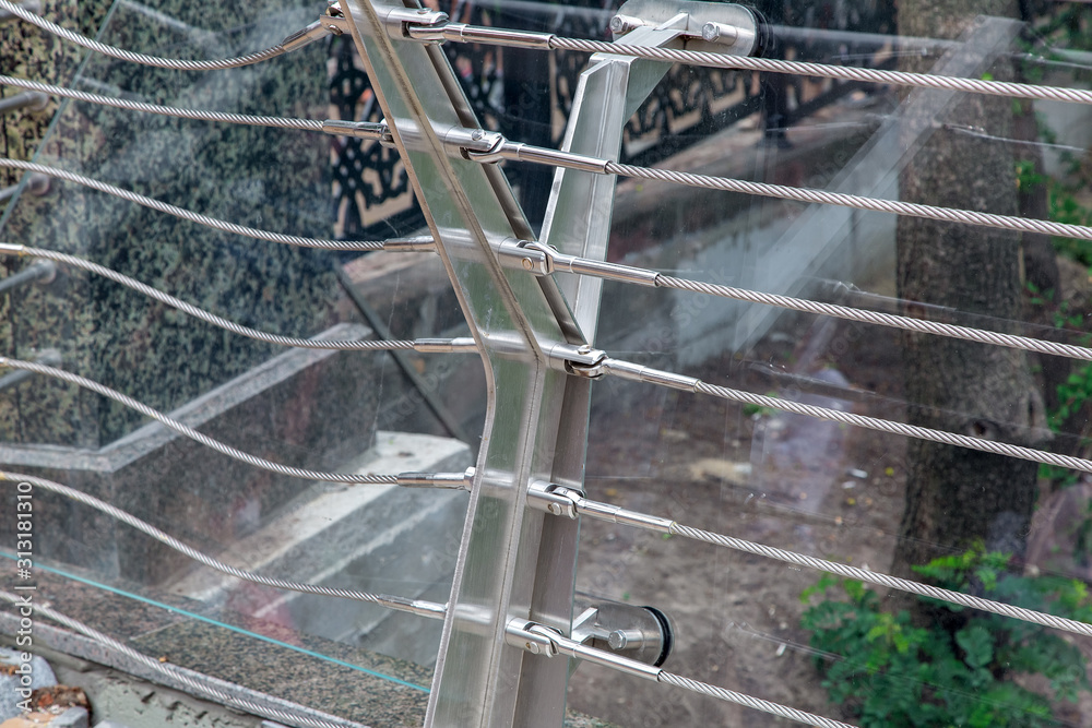 construction details of a glass bridge with steel fasteners and cable tensioners close up.