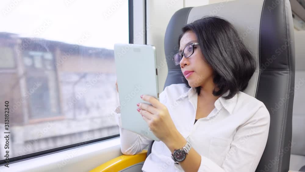 Businesswoman using a tablet while yawning in train Businesswoman using a tablet while yawning in train