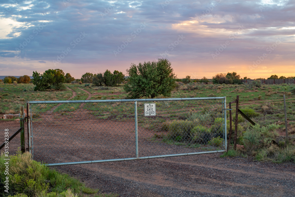 USA, Arizona, Coconino County, Kaibab National Forest, Flagstaff. A stunning sunset behind a fence and a a sign reads 