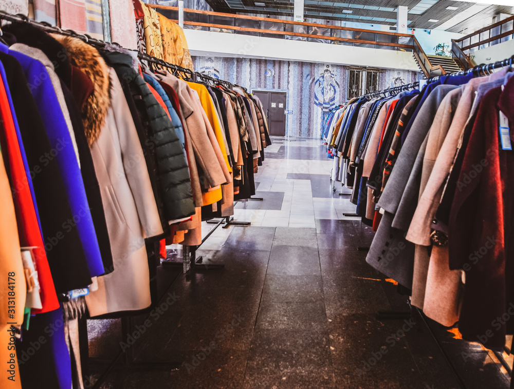 Coats and jackets on hangers in the store. Sale of outerwear.