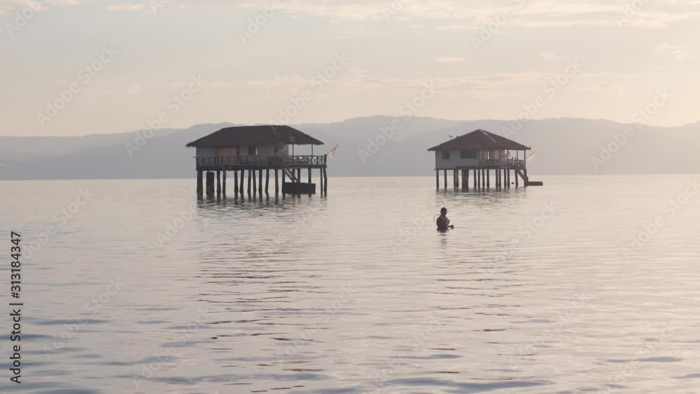Scenic view of calm ocean and bungalow houses in a tropical island. Scenic view of calm ocean and bungalow houses in a tropical island.