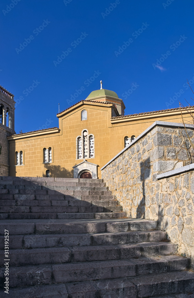 Arahova, Parnassos, Greece, stone steps lead to Agios Georgios (Saint George) church under deep blue sky.