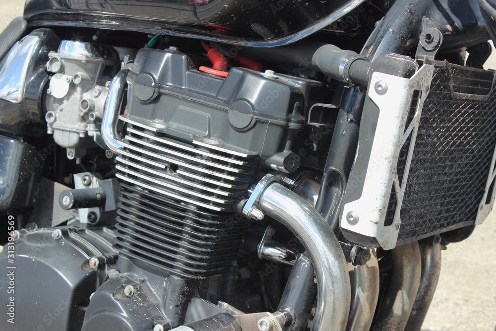 Four cylinder four carburettor four stroke motor bike inline engine with cooling fins and cooling radiator close up