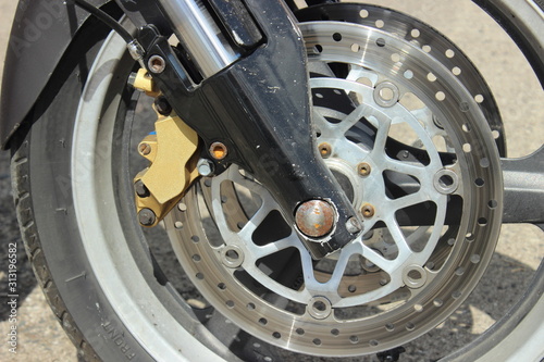 Double perforated disc brakes on Power motor bike front wheel close up 