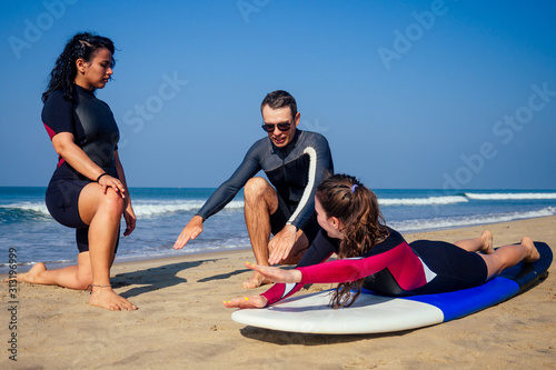 Fotografia, Obraz surf instructor and two girls beginner surfers on lesson in Goa India
