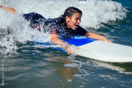 latina-merican beautiful girl surfer instructor catching a wave in summer vacation in Goa indian sea © yurakrasil