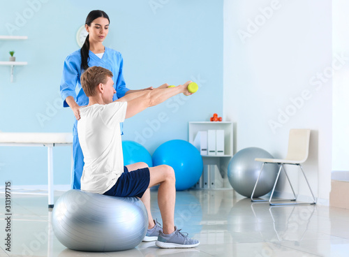 Physiotherapist working with male patient in rehabilitation center photo