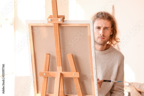 Young male artist painting in studio