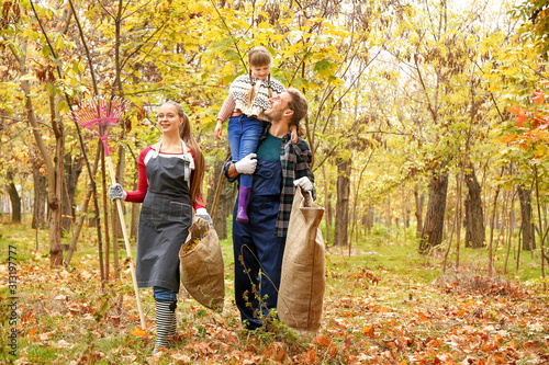 Family cleaning up autumn leaves outdoors © Pixel-Shot