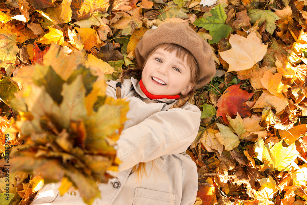 Cute little girl lying on leaves in autumn park Cute little girl lying on leaves in autumn park