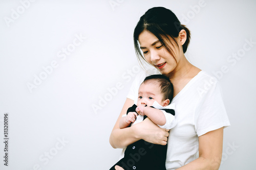 Asian mother hug baby son in her arm at home.