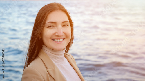 Photography beautiful woman looks ahead and smiles posing against impressive nature and sea