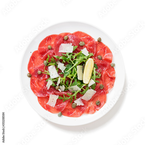 Beef Carpaccio cold appetizer with parmesan, capers and arugula on white plate. isolated on white background