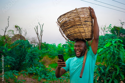 young black happy farmer carrying a basket on his head  photo