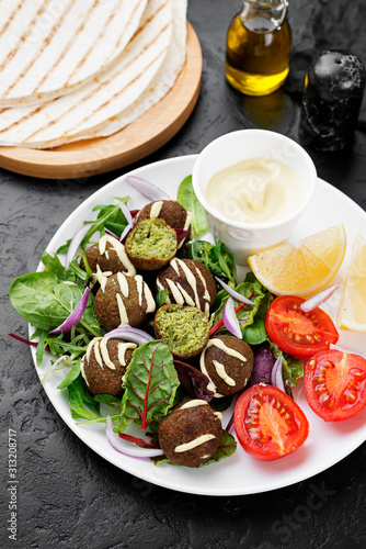 Vegetarian falafel with fresh green salad, sauce and lemon.