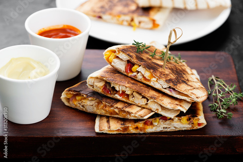 Mexican quesadilla with chicken meat,sweetcorn and pepper served with different sauces. photo