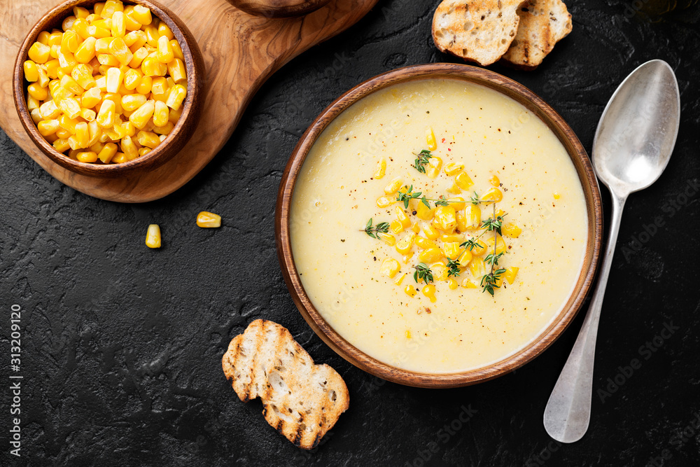 Delicious creamy sweetcorn soup served with toast and corn grains. - obrazy, fototapety, plakaty 