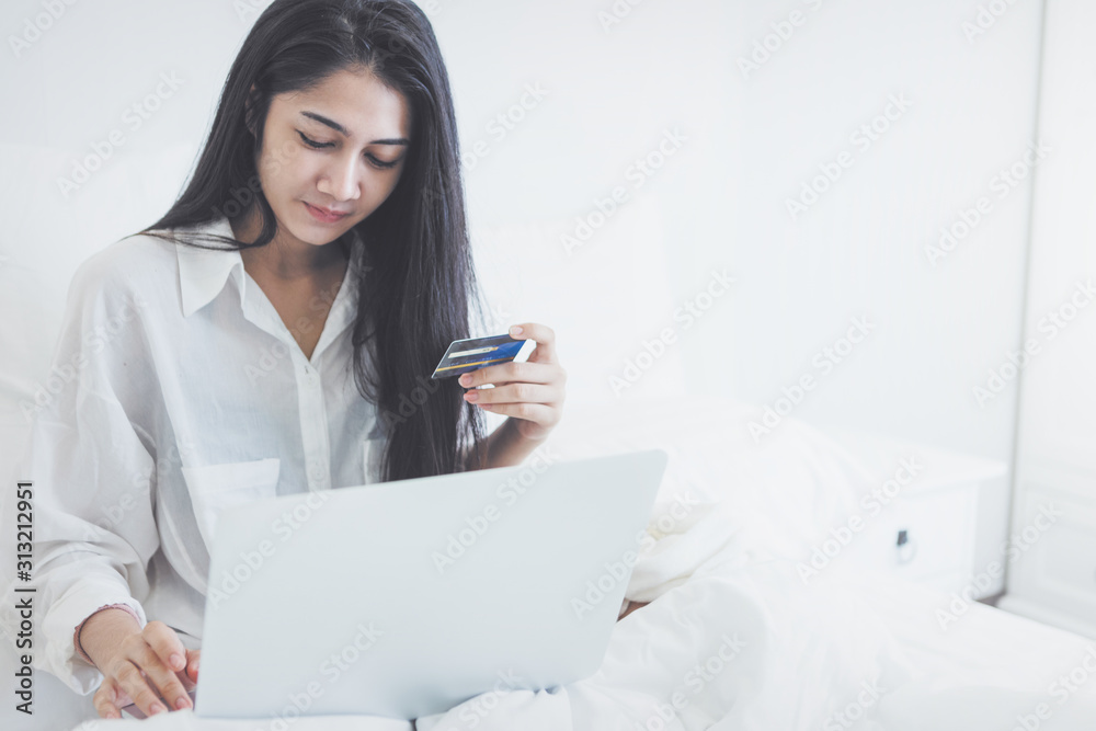 Young women using credit card for shopping online and buy tickget to travel with labtop in bed at morning ;Morning relax time for shopping online Young women using credit card for shopping online and buy tickget to travel with labtop in bed at morning ;Morning relax time for shopping online