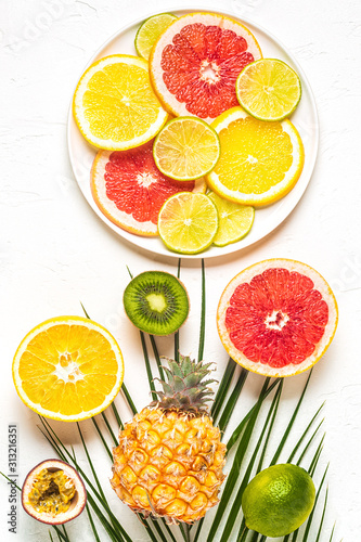 Tropical fruits and palm leaves on a white background.