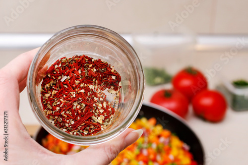 Woman is holding a jar with spices in her hand.