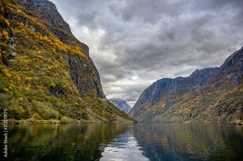 Mountains in the autumn season that reflect the water. Watch from a boat trip to see the beauty of Sognefjord Cruise  program from Gudvangen to Flam in Norway.