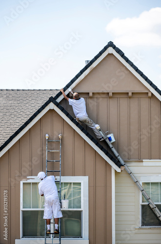 Tablou pe pânză House painters paint the facade of a house standing on ladders