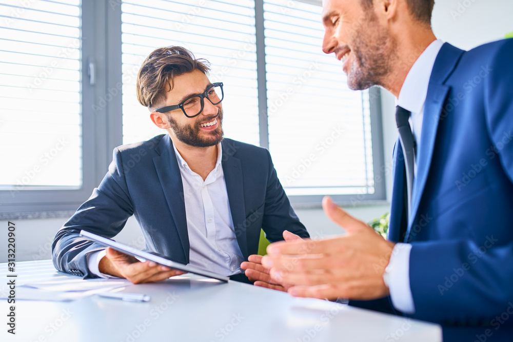 Shot of two positive businessmen discussing during office meeting