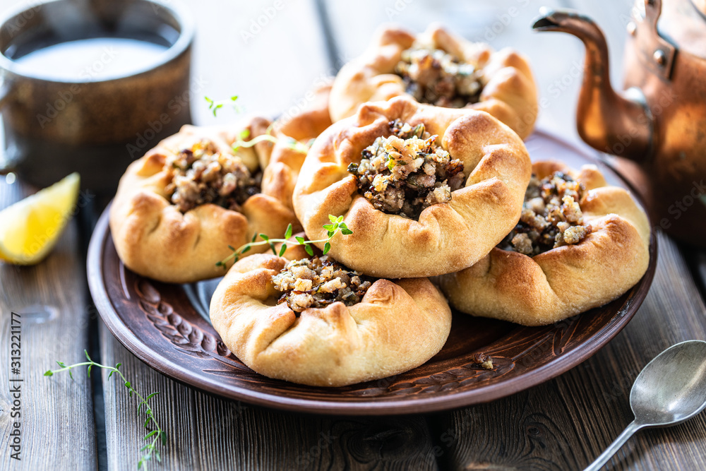 Group of individual pies with meat and potato - vak balish. Tatar traditional pies. Wooden background.