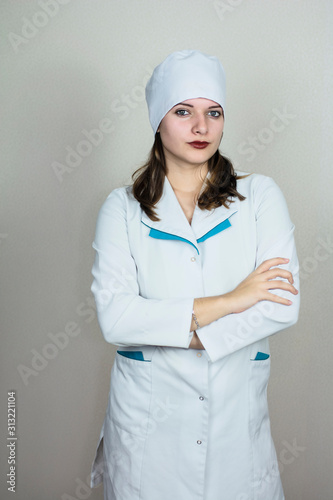 doctor woman in white coat with dark hair  on light background photo