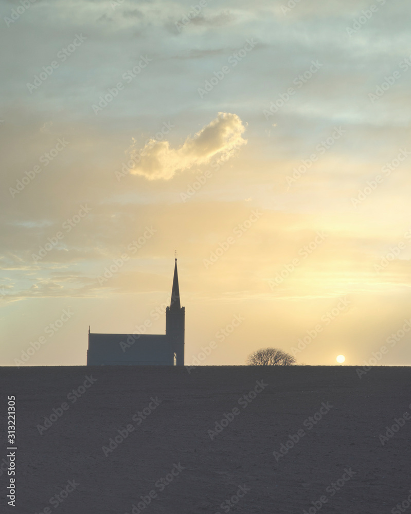 Church chapel silhouette building and tree with large sky place of religious worship during sunset at St Cyrus Angus Scotland UK