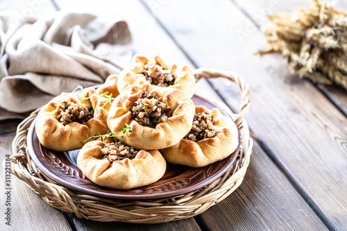 Group of individual pies with meat and potato - vak balish. Tatar traditional pies. Wooden background photo