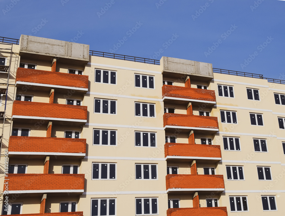 wall of a high-rise brick house, red balconies and yellow walls.