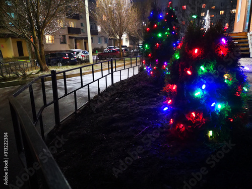 Christmas tree decorated with glittering toys shines beautifully with colorful lights in the dark