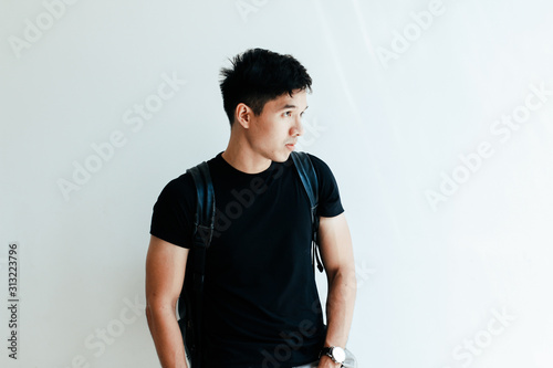 Young handsome asian boy wearing black plain shirt and backpack at day in Sai Gon city, Vietnam - Casual lifestyle of Vietnamese teenager