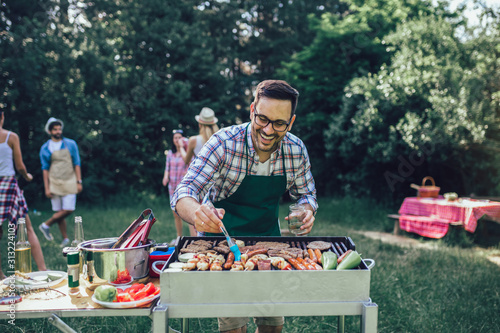 Tela Handsome male preparing barbecue outdoors for friends