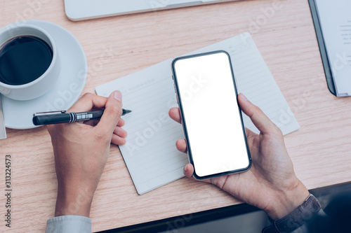 Mockup image blank white screen cell phone.man hand holding texting using mobile on desk at office.background empty space for advertise text.people contact marketing business,technology 