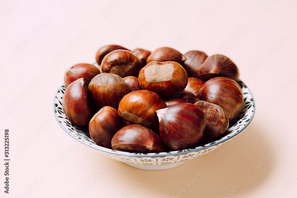 A nice bowl of chestnuts on beige background A nice bowl of chestnuts on beige background